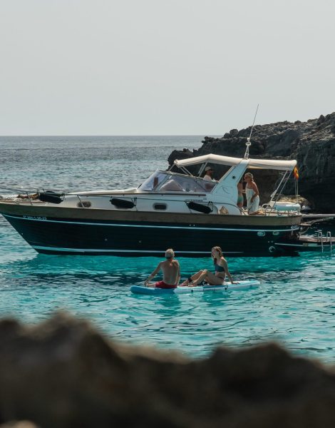 Barco clásico navegando con grupo de personas a bordo, disponible para alquiler con una cabina y un baño en Menorca.